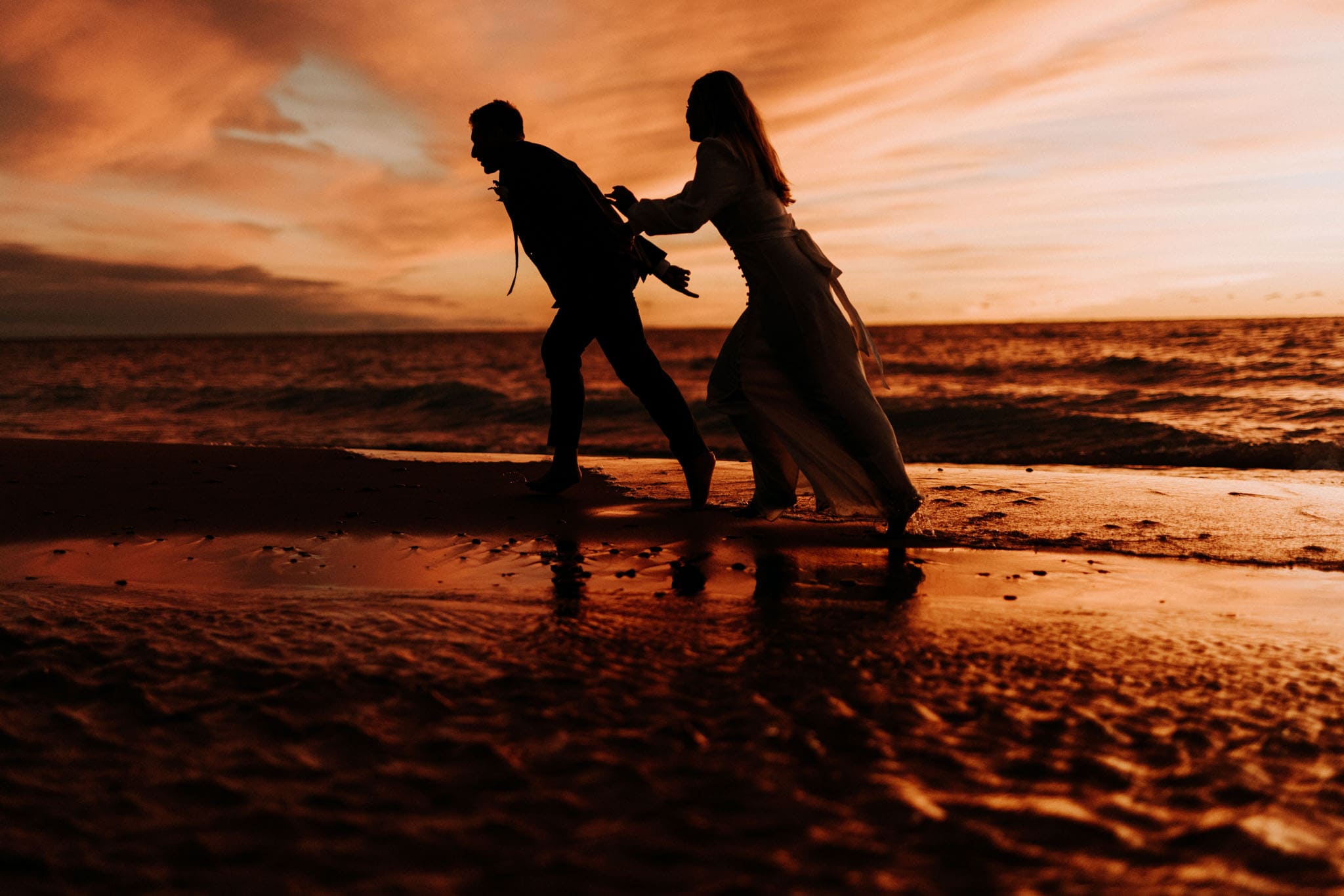 Couple silhouetted at sunset on Lake Michigan beach — wedding photography by michael kent